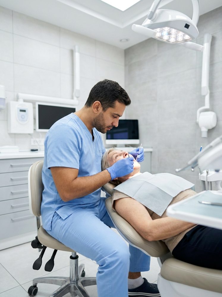 Dentista atendendo paciente na cadeira em consultório odontológico moderno